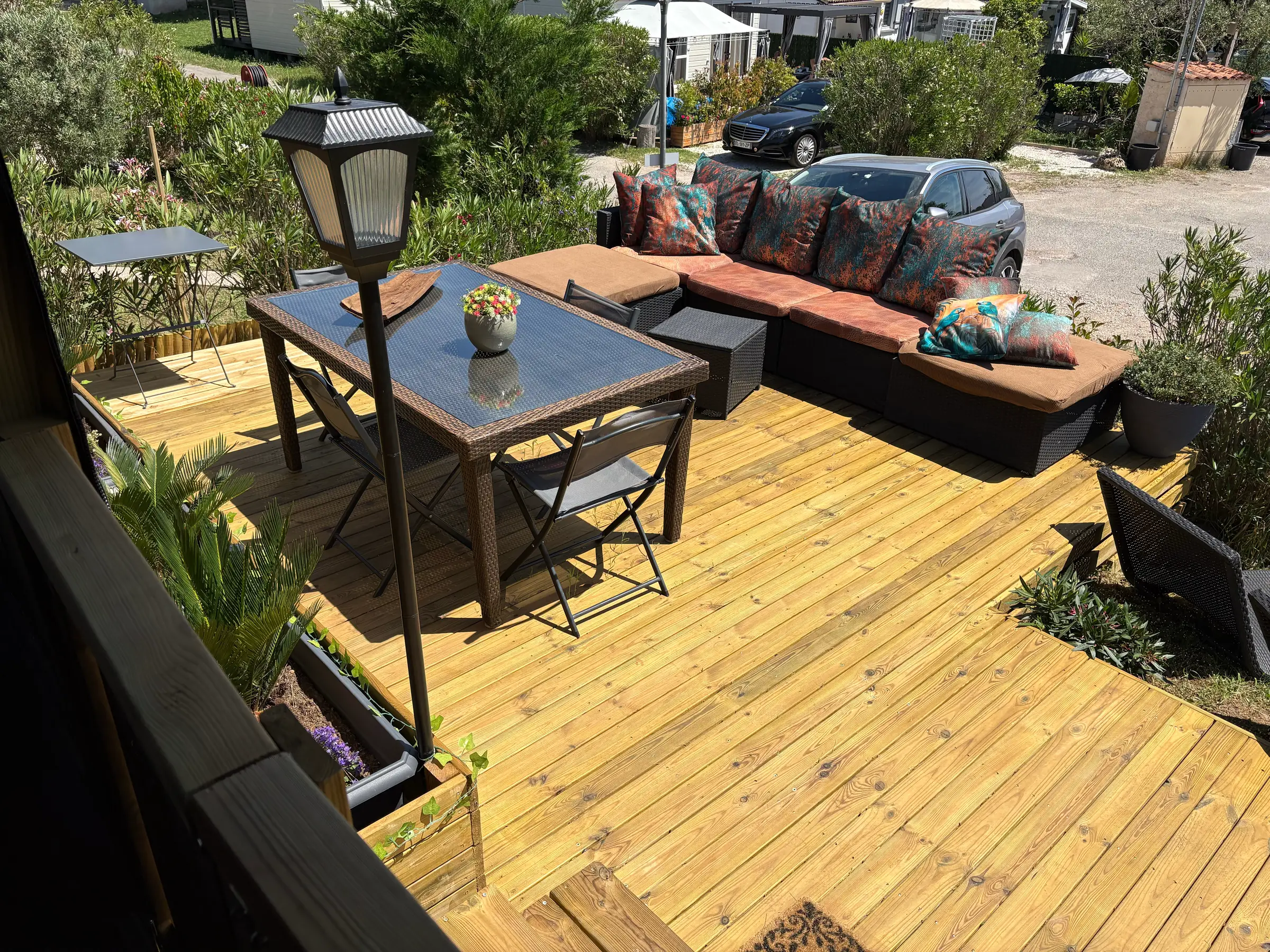 Salon d'angle en résine tressée et table haute sur le deck en bois