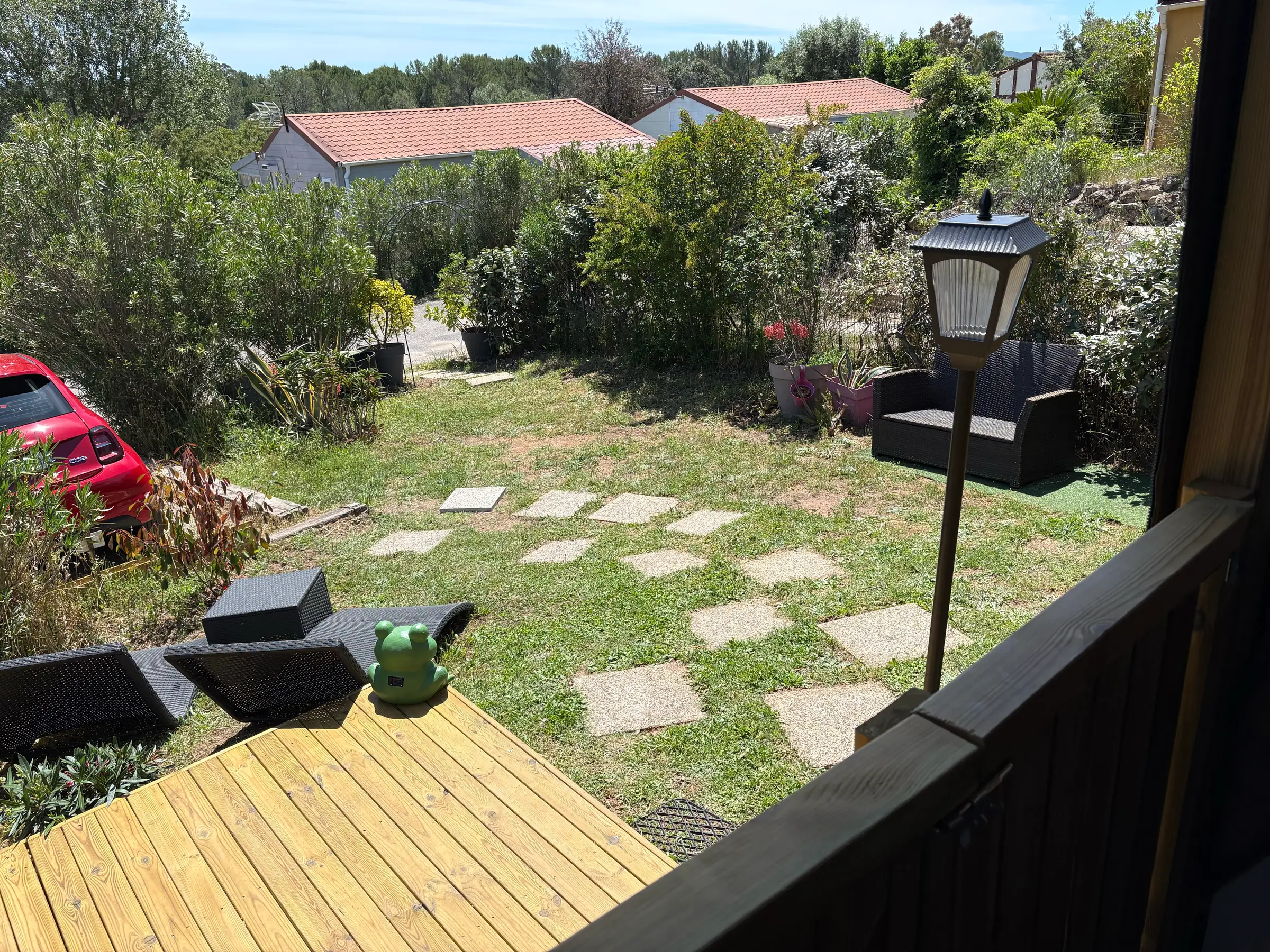 Jardin privatif engazonné avec allée de dalles et fauteuil d'extérieur