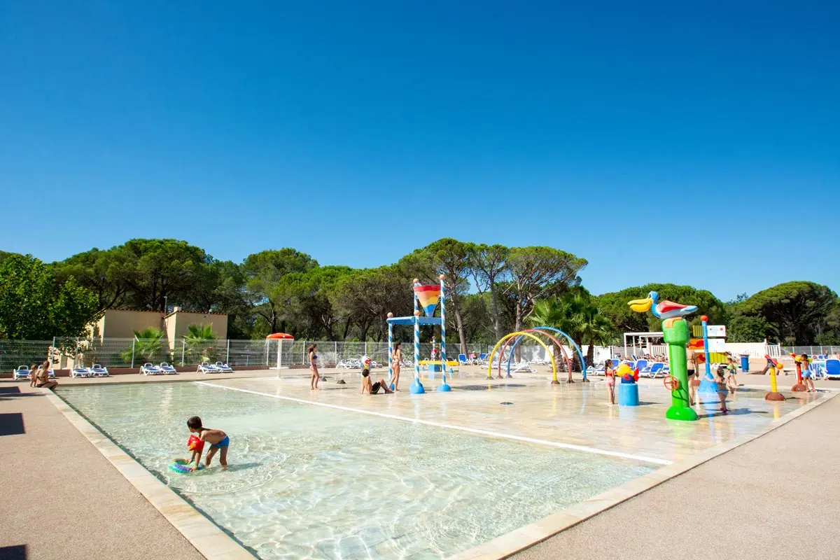 Pataugeoire et jeux d'eau pour les enfants, bordés de pins