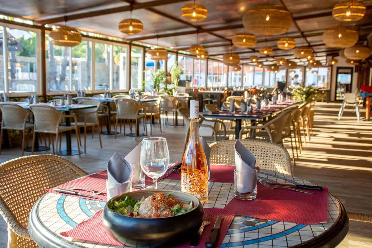 Salle du restaurant du domaine, tables dressées et suspensions en rotin
