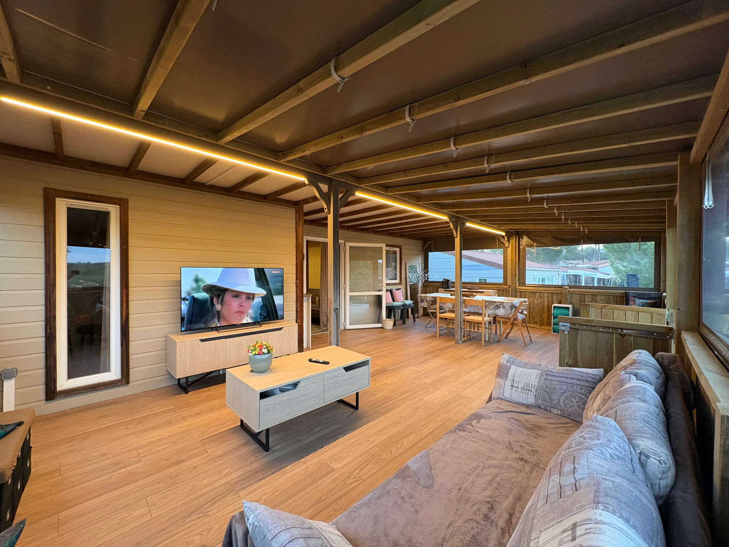 Terrasse fermée de 35 m² avec charpente apparente, salon et table de repas
