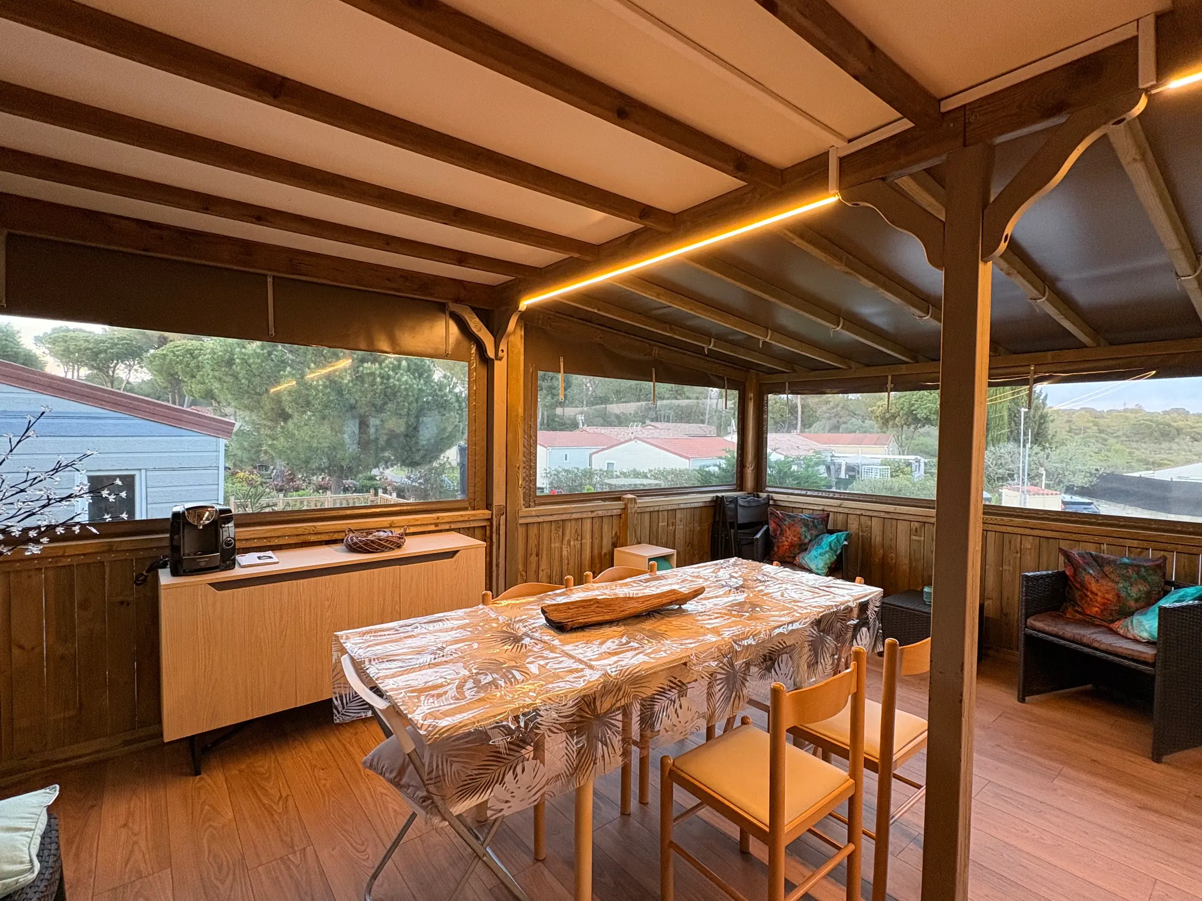 Table de repas dressée pour huit sous la charpente de la terrasse couverte
